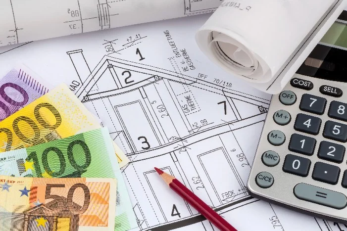 Bauplan eines Hauses mit Euro-Banknoten und einem Taschenrechner